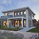 La photo montre une maison moderne de deux étages au crépuscule, dont l'éclairage intérieur crée une ambiance accueillante. La maison est entourée d'un jardin paysager bien entretenu, avec de la lavande en fleurs au premier plan, et dispose d'une terrasse spacieuse avec des sièges.