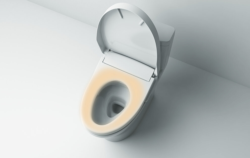 L'image montre un Washlet vu de dessus. Le couvercle est ouvert. L'assise est mise en évidence par la couleur orange.