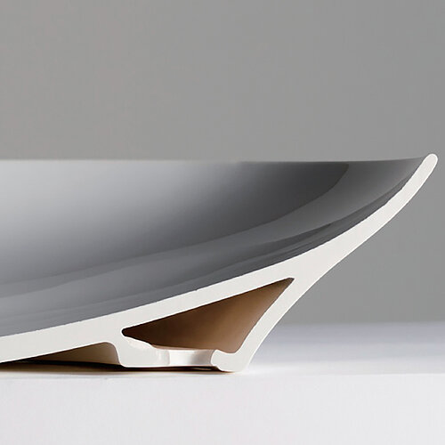 The picture shows a washbasin fitted with Lineceram. The washbasin is divided in the middle so that you can see the inside. The lower part, with which the washbasin stands on the floor, is a cavity. This cavity is located under the washbasin as a base. The hollow space closes at the top so that the upper part consists of a single ceramic. 