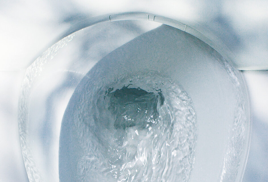 Vue d'en haut de la céramique des toilettes. L'eau s'écoule en spirale dans l'évacuation.