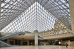 Gläserne Eingangshalle mit Rolltreppe im Louvre Museum in Paris | TOTO Europe Eingangsbereich des Louvre Museums in Paris
